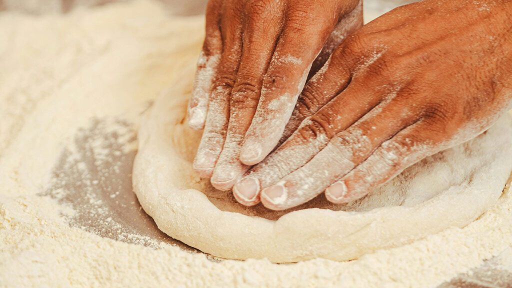 Nahaufnahme von Händen die einen Teig kneten 