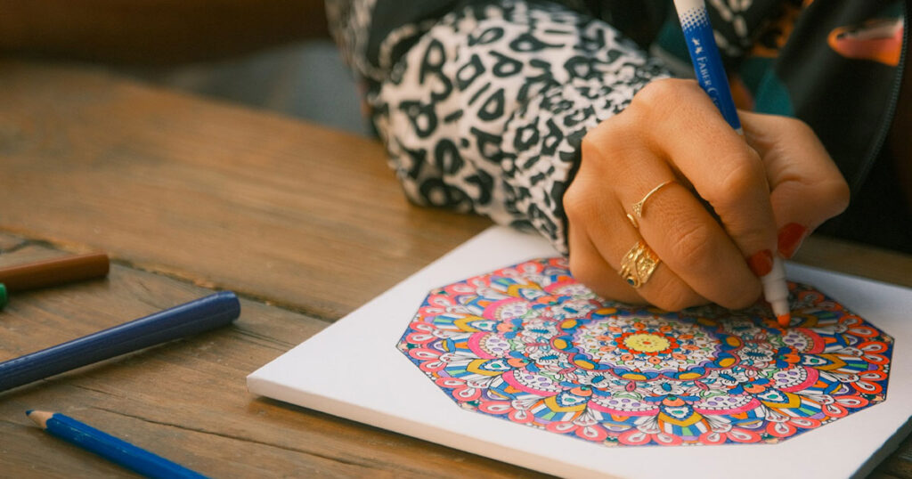 Nahaufnahme: Malbuch für Erwachsene mit einer Hand und einem Buntstift