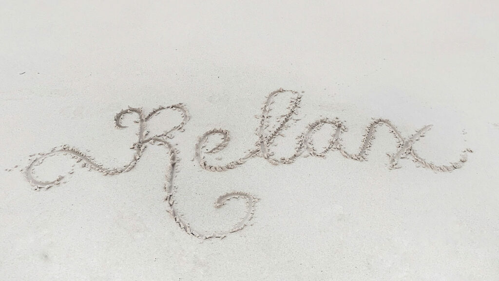 Das Wort Relax in Sand geschrieben